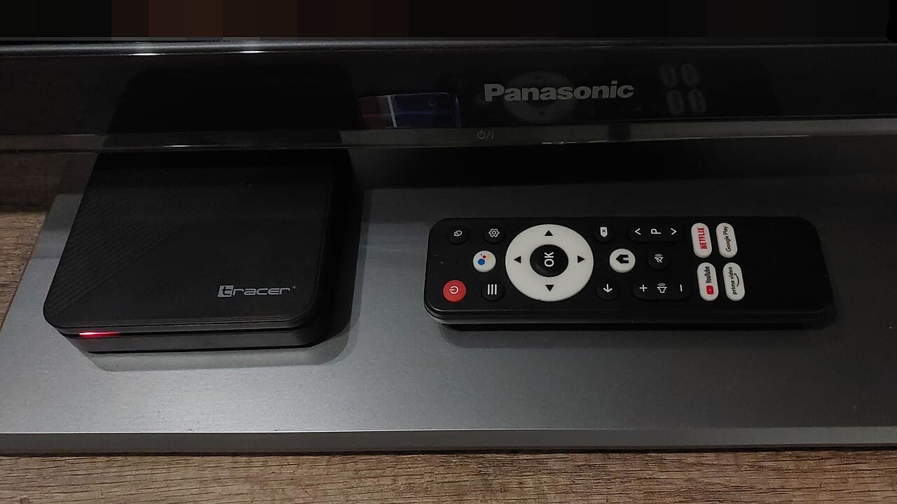 A Tracer Android TV set-top box on a wooden desk, next to a remote.